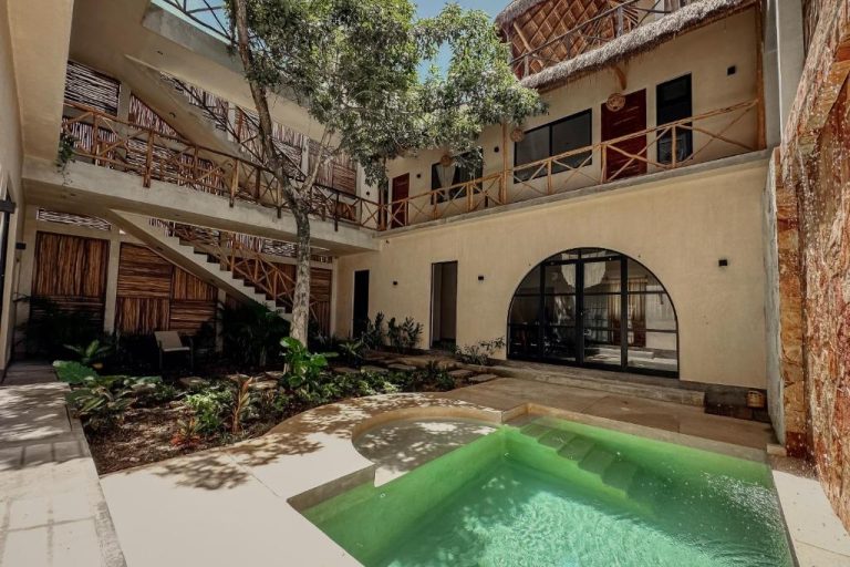 Piscina privada en el patio interior de Casa Kobaab Tulum con jardín tropical y balcones de madera