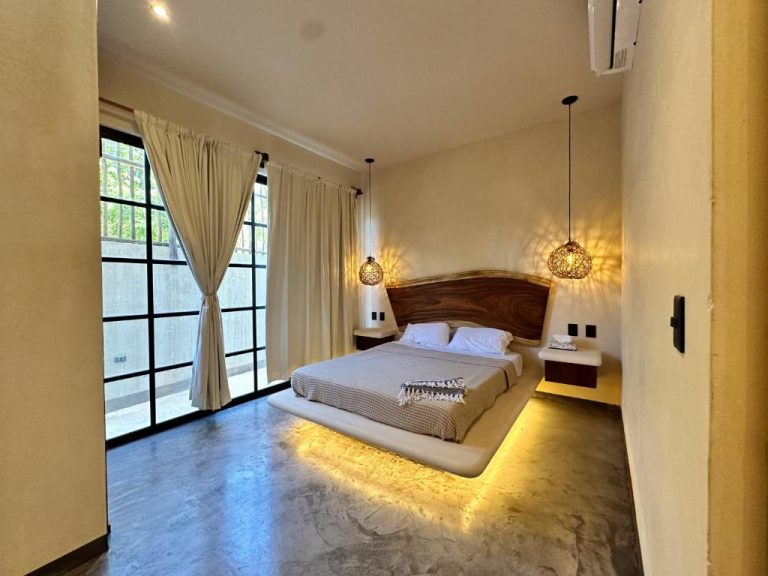 Habitación con cama flotante iluminada y cabecero de madera natural en Casa Kobaab Tulum