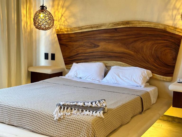 Habitación con cabecero de madera natural artesanal y lámpara de mimbre en Casa Kobaab Tulum