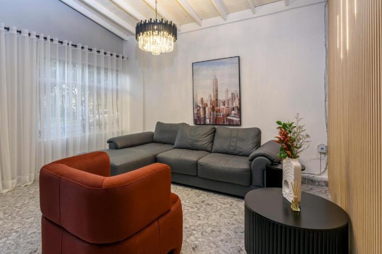 Sala de estar moderna con sofá de cuero gris y sillón rojo en Hotel Hola Medellín