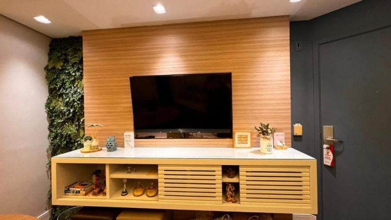 Sala de estar con TV empotrada en panel de madera y jardín vertical en Flat Sena Madureira