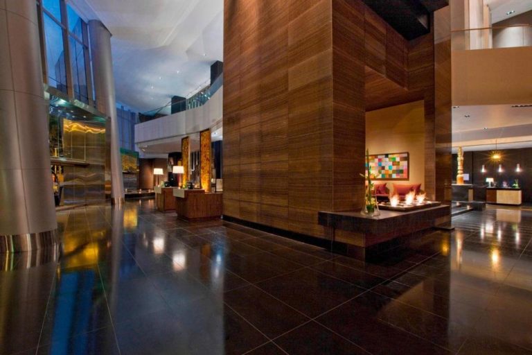Lujoso lobby del The Westin Lima Hotel con suelos de mármol oscuro y decoración contemporánea en madera