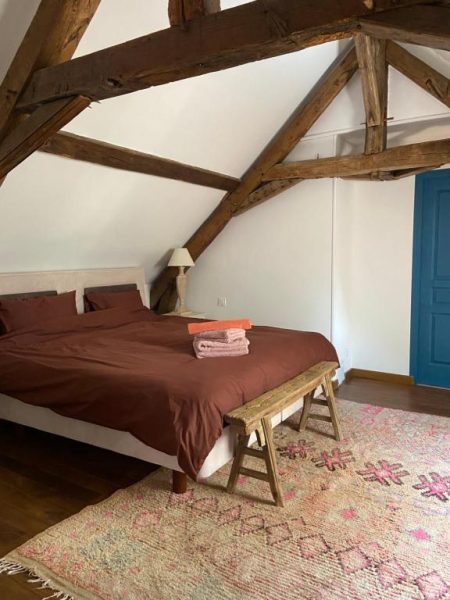 Habitación abuhardillada con vigas de madera y cama doble en Moulin de Petoulle