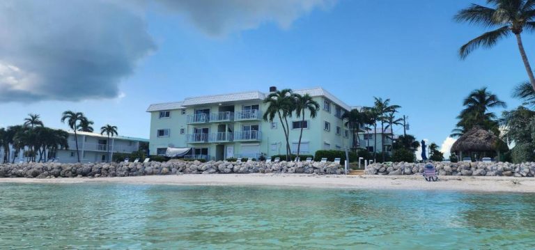 Vista exterior del hotel Key Colony Beach desde el mar con playa de arena blanca y palmeras en Florida Keys