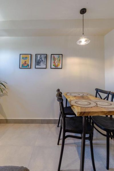 Comedor con mesa de madera natural y sillas negras en De la Cruz Studio Apartments