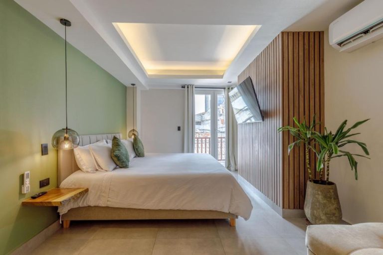 Habitación doble moderna con pared verde y detalles en madera en De la Cruz Studio Apartments