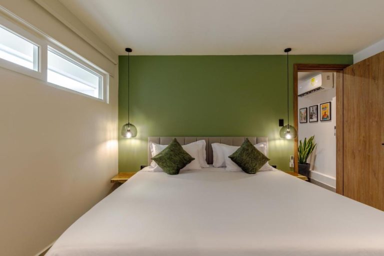 Habitación doble con pared verde y cama king size en De la Cruz Studio Apartments