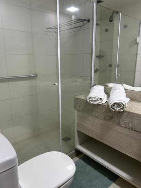 Baño moderno con ducha de cristal y toallas blancas en Suite Incrível Sonhos e Praia