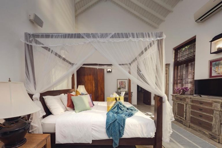 Habitación con cama de dosel y mosquitera blanca en La Maison de Colombo, decoración colonial tropical