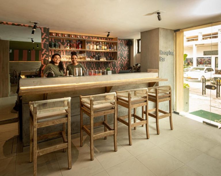 Bar y recepción con taburetes de madera y estantería de bebidas en Mood Matuna Hotel Cartagena