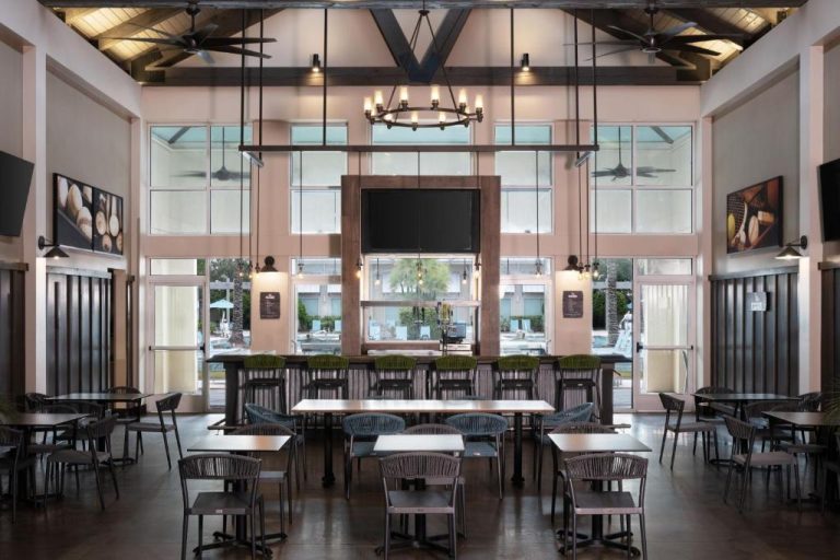 Bar y restaurante interior con mesas y sillas del SpringHill Suites Orlando Flamingo Crossings con vistas a la piscina