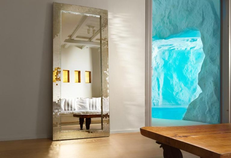 Habitación de lujo con espejo dorado y vistas a la piscina gruta en Cavo Tagoo Mykonos