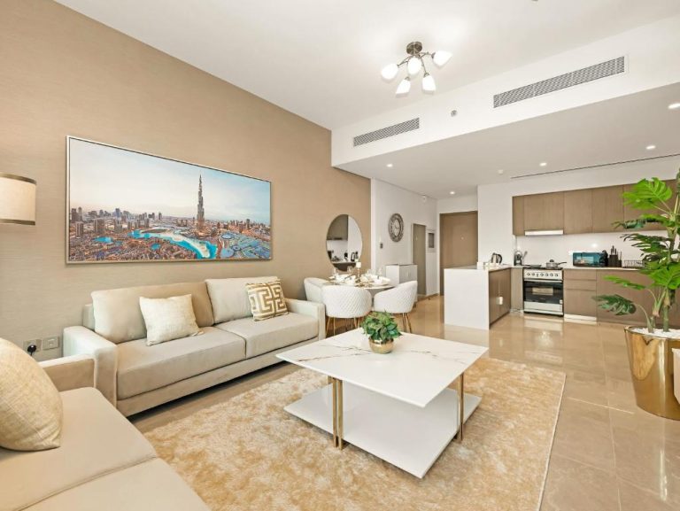 Salón moderno con cocina abierta y cuadro del Burj Khalifa en apartamento de lujo cerca de Dubai Mall