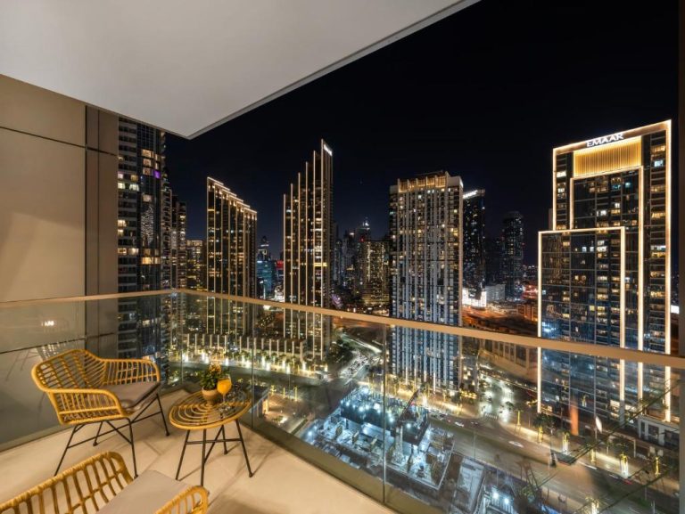 Terraza con vistas nocturnas al skyline de Dubai y edificio Emaar desde apartamento de lujo cerca del Dubai Mall