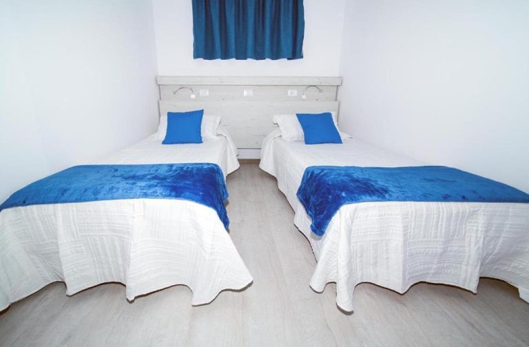 Habitación twin con dos camas y ropa de cama azul y blanca en Apartamentos Monte Verde