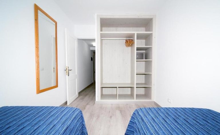 Habitación twin con armario empotrado abierto y espejo en Apartamentos Monte Verde