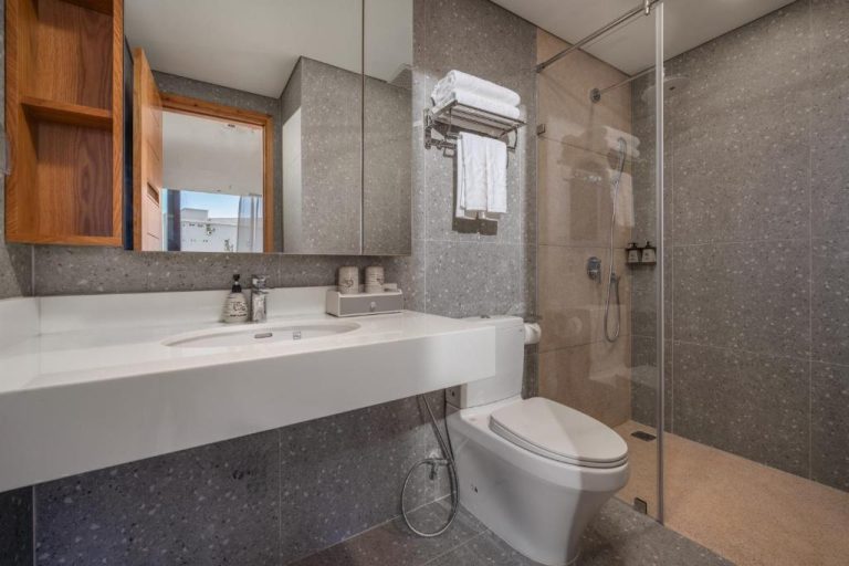 Baño moderno con ducha de cristal y lavabo blanco en Vernal Hotel & Apartment Da Nang