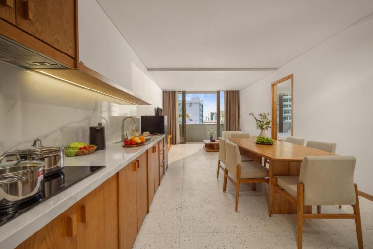 Cocina equipada y comedor con mesa de madera en apartamento del Vernal Hotel Da Nang