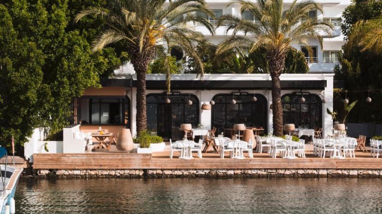 Terraza exterior con mesas y sillas blancas del Yacht Classic Hotel Boutique frente al mar