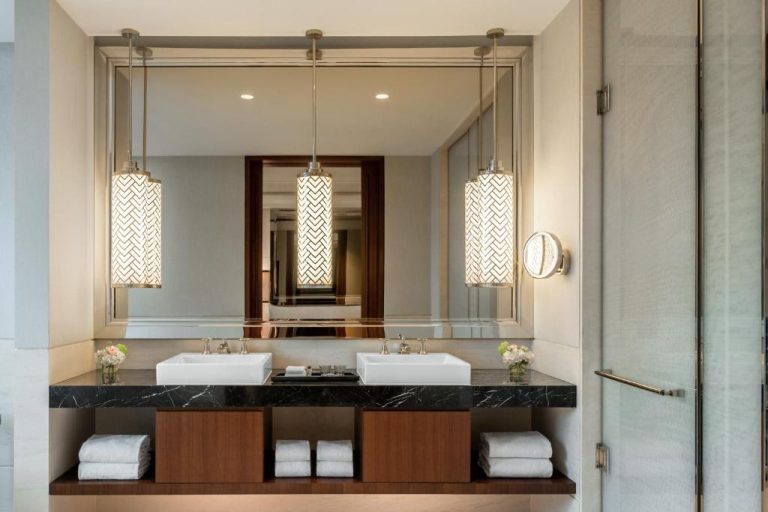 Baño de lujo con doble lavabo y encimera de mármol negro en The Capitol Kempinski Hotel Singapore