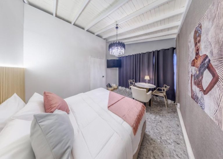 Habitación doble de lujo con cama king, araña de cristal y decoración elegante en Hotel Hola Medellín