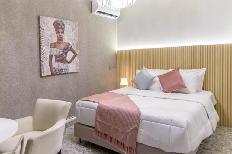 Habitación doble de lujo con cama king size y decoración elegante en rosa del Hotel Hola Medellín