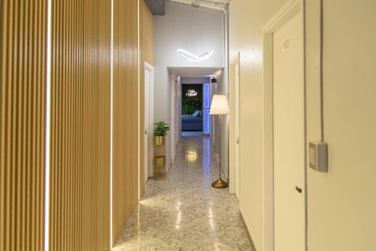 Pasillo interior moderno con decoración dorada y neón del Hotel Hola Medellín en Colombia