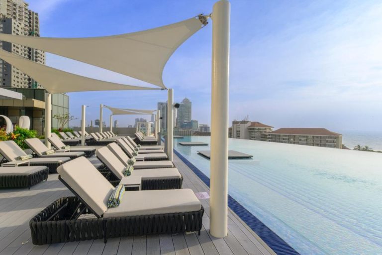 Piscina infinita con tumbonas y vistas al mar en el hotel Cinnamon Life at City of Dreams
