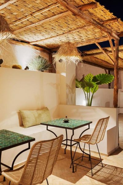 Terraza exterior con mesas de mosaico verde y sillas de ratán en Riad Dar Acsameda Spa Marrakech