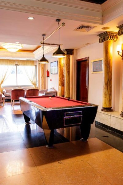 Mesa de billar con tapete rojo en la sala de recreación del Cesar Palace Sousse con columnas decorativas
