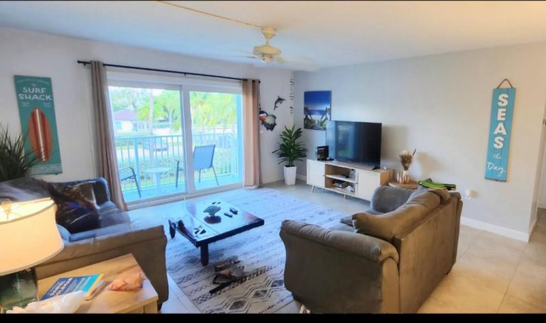 Sala de estar con decoración tropical y vistas al exterior en Paradise Key Colony Beach