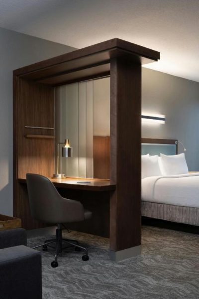 Escritorio de trabajo iluminado con silla ergonómica junto a cama doble en SpringHill Suites Orlando Flamingo Crossings