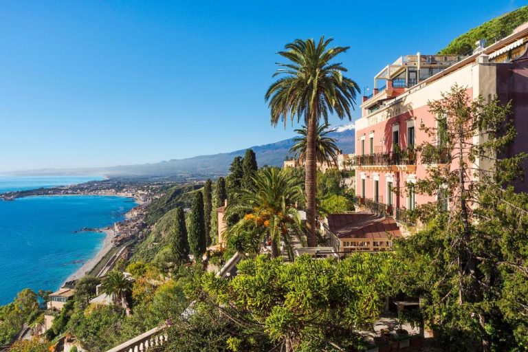 Vista panorámica del Hotel Villa Schuler en Taormina con jardines, palmeras y vistas al mar y al Etna