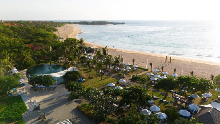Vista aérea de la piscina exterior y playa privada del Ayodya Resort Bali con tumbonas y palmeras