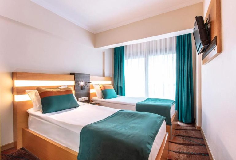Habitación twin con dos camas y decoración en turquesa del Hotel Ilayda con televisión de pared