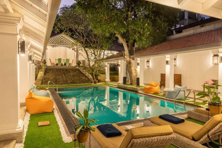 Piscina exterior con tumbonas y jardín iluminado del hotel La Maison de Colombo en Sri Lanka
