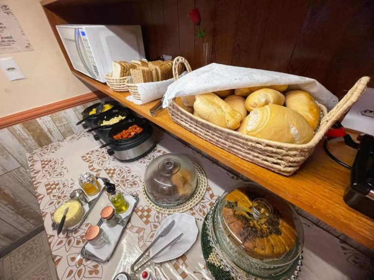 Mesa de desayuno buffet con panes frescos, frutas y embutidos en Refúgio Pousada Fortaleza