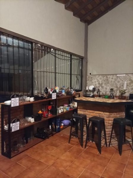 Cocina y bar común con estantes de madera y taburetes en Habitaciones Dos Antonios