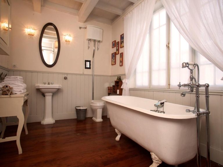 Baño clásico con bañera exenta de pie en Quinta Miraflores Boutique Hotel, suelo de madera y decoración vintage