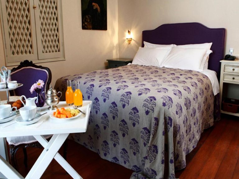 Habitación doble con desayuno en bandeja y cama con cabecero morado en Quinta Miraflores Boutique Hotel