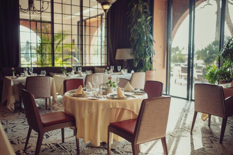 Elegante restaurante interior del Tikida Golf Palace con mesas vestidas y vistas al jardín