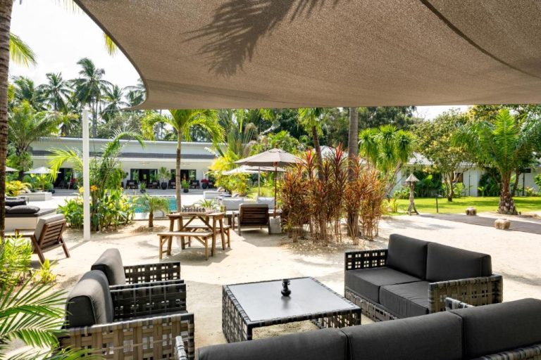 Terraza exterior con sofás y jardín tropical del Moorea Boutique Resort Samui en Tailandia