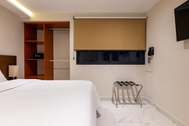 Habitación doble con cama, armario empotrado y ventana con persiana en Hotel 28 Cancún