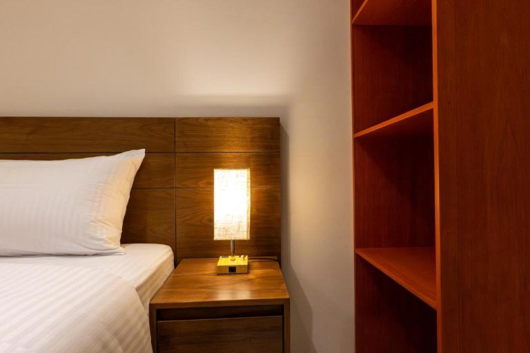 Habitación con cama doble, mesita de noche con lámpara y estantería de madera en Hotel 28 Cancun