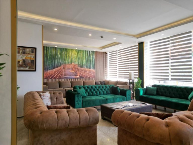 Amplio salón con sofás verdes y marrones del Akman City Hotel con decoración moderna y cuadro de bambú