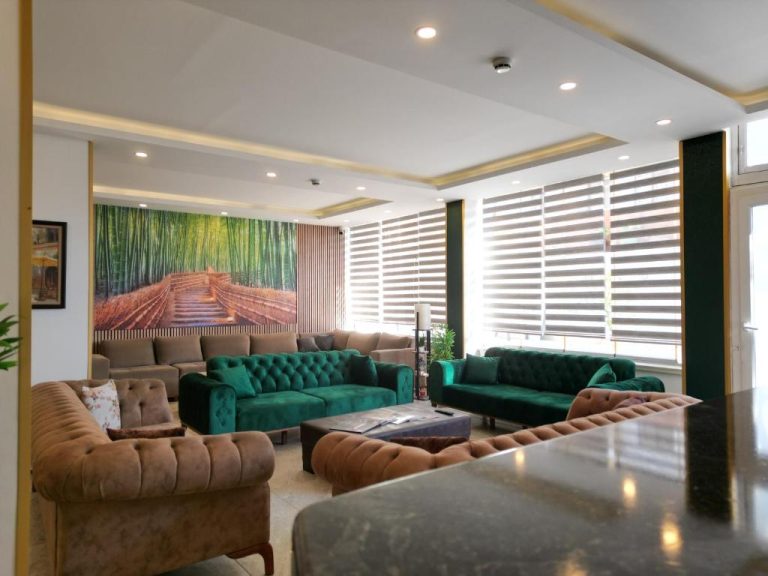Amplio salón del Akman City Hotel con sofás verdes y beige, cuadro decorativo y ventanas con estores