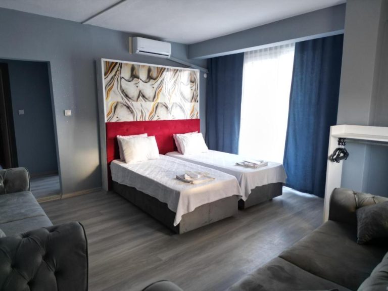 Habitación doble con cabecero rojo y panel mármol del Akman City Hotel con sofás grises