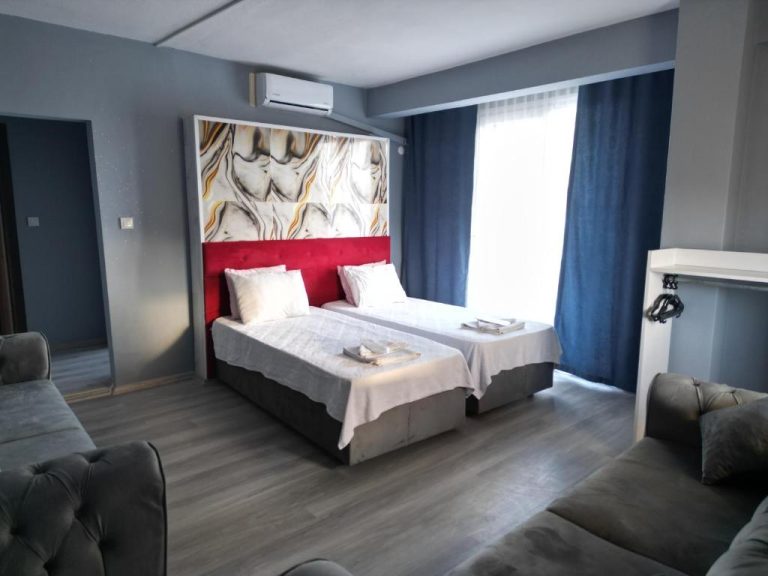 Habitación doble con cabecero rojo y decoración mármol en Akman City Hotel con sofás y cortinas azules