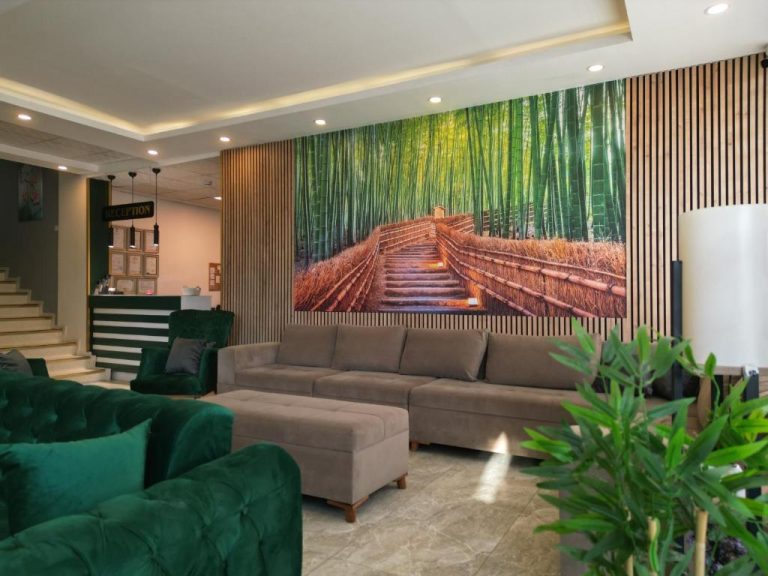 Lobby del Akman City Hotel con sofás verdes y mural de bosque de bambú en la recepción