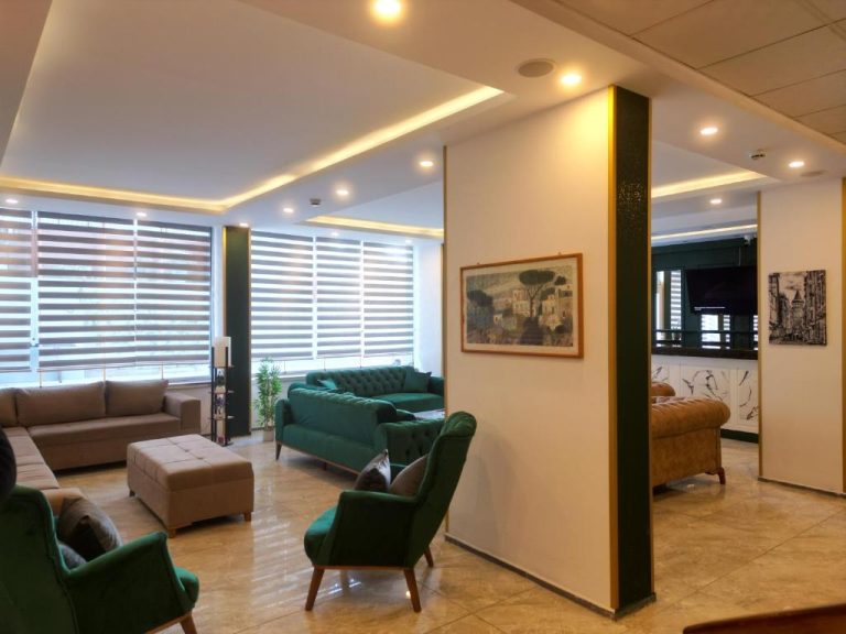 Amplio salón lobby del Akman City Hotel con sofás verdes, iluminación moderna y grandes ventanales